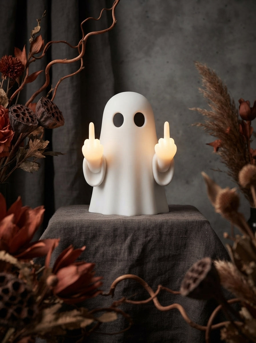 A premium white ghost figurine holding a glowing night light on its finger, displayed on charcoal fabric with terracotta acce